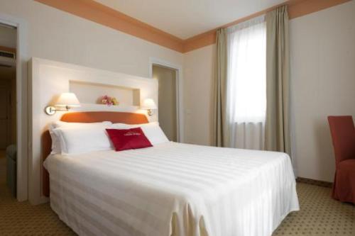 a bedroom with a large white bed with a red pillow at Cora Hotels Leon d'Oro in CastellʼArquato