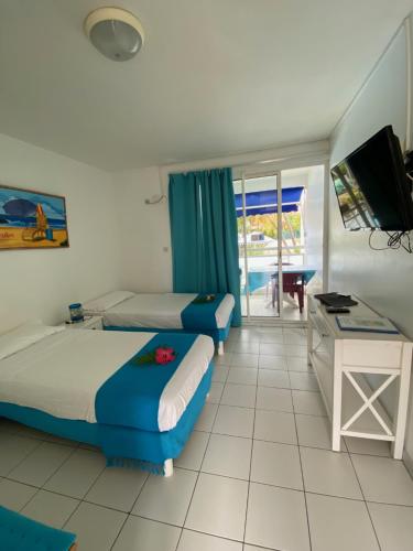 1 Schlafzimmer mit 2 Betten, einem Schreibtisch und einem TV in der Unterkunft Les Créolines in Sainte-Luce