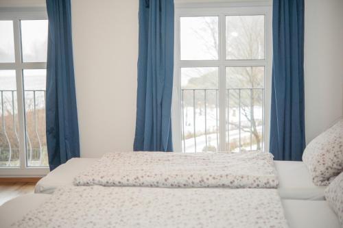 a bedroom with a bed with blue curtains and a window at Landgasthof Witten in Labenz