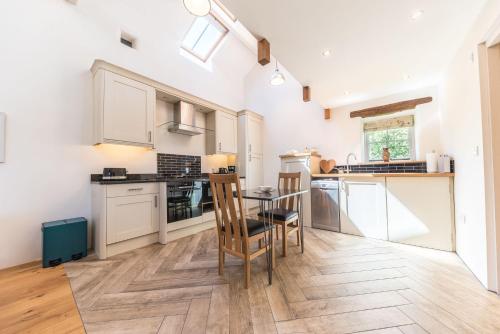 a kitchen with white cabinets and a table and chairs at Mill Pool Barn Torver, Coniston in Coniston