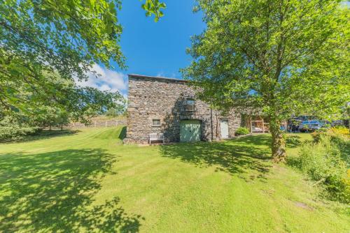 an old stone barn with a tree in the yard at Mill Pool Barn Torver, Coniston in Coniston
