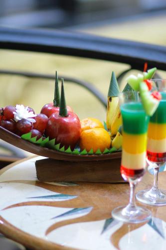 a plate of fruit on a table with two glasses at The Grand Palace Hotel Malang in Malang