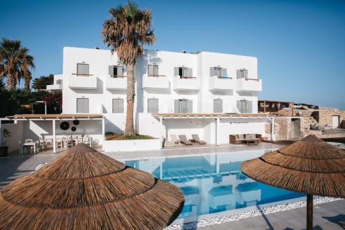 a hotel with two straw umbrellas next to a swimming pool at Paros Bay in Parasporos