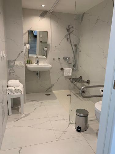 a white bathroom with a sink and a toilet at Hotel Agaró in Chipiona