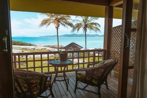 a balcony with a table and chairs and the ocean at Hotel Atalaia do Mariscal in Bombinhas