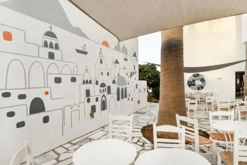 a room with white chairs and a wall with a mural at Paros Bay in Parasporos