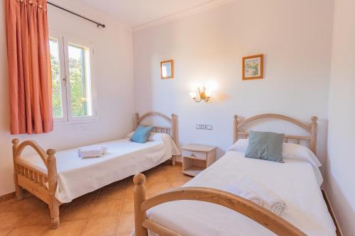 1 dormitorio con 2 camas y ventana en Villa Llebeig 155TS Son Bou By MENORCARENTALS, en Son Bou