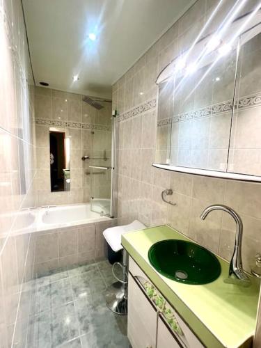 La salle de bains est pourvue d'un lavabo vert et d'une baignoire. dans l'établissement Incroyable appartement parisien - Batignolles, à Paris