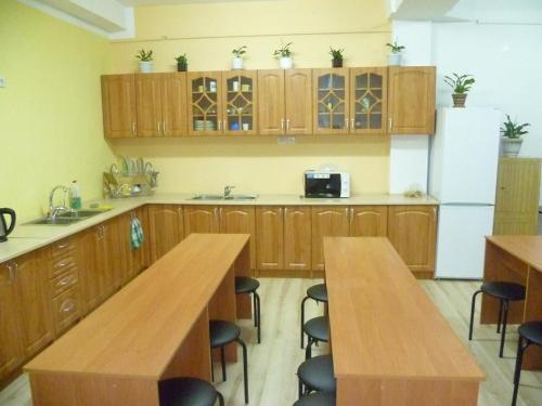 a kitchen with wooden cabinets and wooden tables and a refrigerator at Hostel Vitan in Lviv