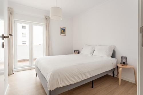 ein weißes Schlafzimmer mit einem großen Bett und einem Fenster in der Unterkunft Lisbon Vibes - Monsanto house in Lissabon