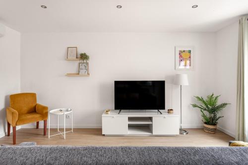 a white living room with a tv and a chair at Lisbon Vibes - Monsanto house in Lisbon