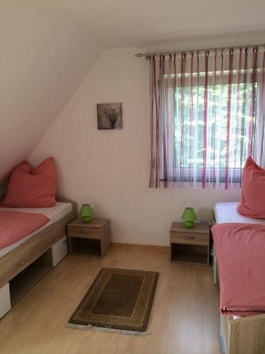 Un dormitorio con 2 camas y una ventana con sábanas rosas. en Ferienwohnung Angela, en Neuenkirchen