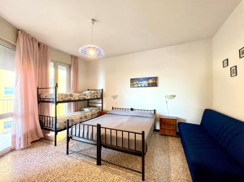 a bedroom with two bunk beds and a blue couch at Appartamenti Fronte Mare CC - Carraro Immobiliare Jesolo - Family Apartments in Lido di Jesolo