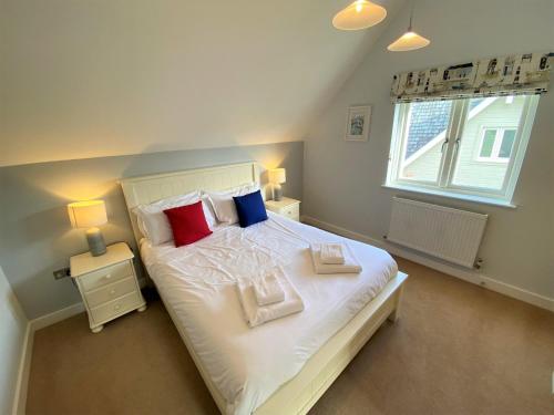 ein Schlafzimmer mit einem Bett mit Kissen und einem Fenster in der Unterkunft Trewhiddle Villa 29 in St Austell
