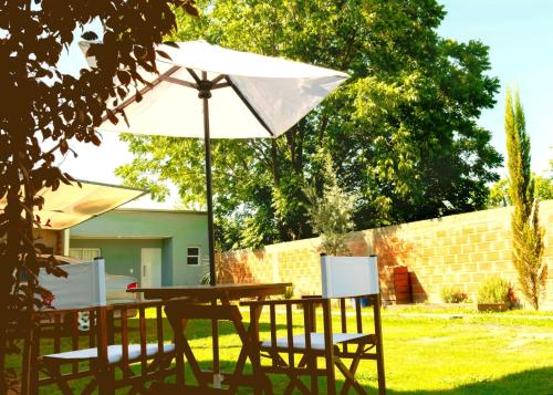 Una mesa y sillas con una sombrilla en un patio. en Vina, en Villa Elisa