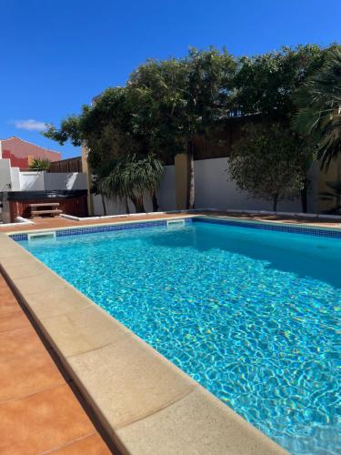 a blue swimming pool with trees in the background at Casa Del Medio in Antigua