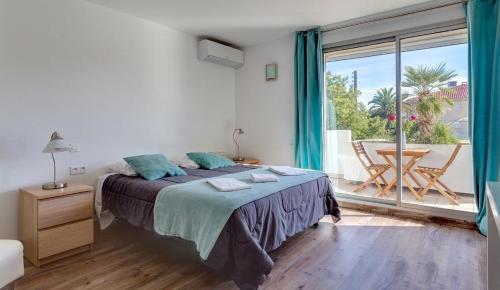 a bedroom with a bed and a large window at Hotel Sable Et Soleil - Port, Plage et spa in Fréjus