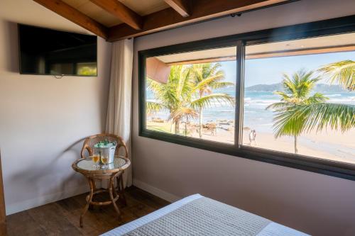 a room with a window with a view of the beach at Hotel Atalaia do Mariscal in Bombinhas