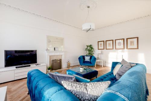 a living room with blue couches and a tv at Heart of Edinburgh City Centre 3 Bed Georgian Apt in Edinburgh