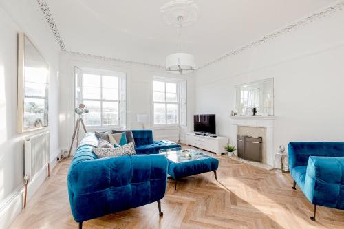 a living room with blue couches and a fireplace at Heart of Edinburgh City Centre 3 Bed Georgian Apt in Edinburgh
