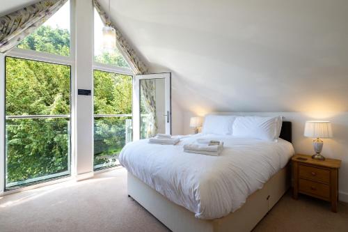 a bedroom with a large white bed and large windows at Trewhiddle Retreat V27 by Together Travel - Luxury 3-Bedroom Villa in St Austell