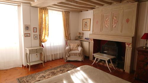 a living room with a fireplace and a chair at A l'Ombre du Tilleul in Giverny