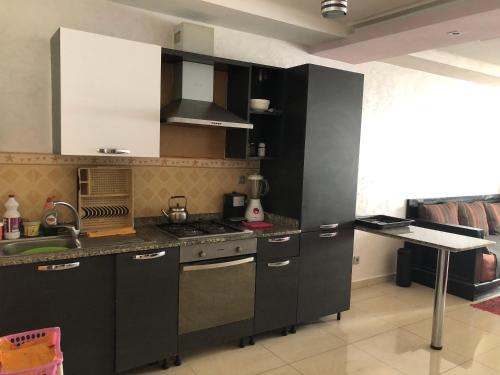 - une cuisine avec des placards noirs et blancs et un évier dans l'établissement Appartement, à Agadir