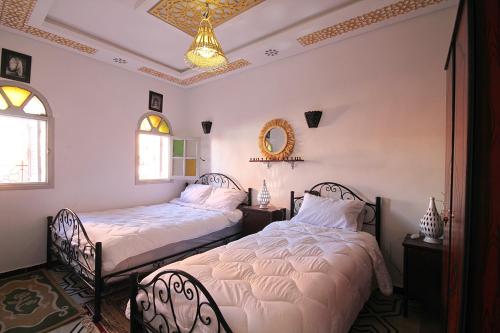 two beds in a room with two chairs and a ceiling at Araf House in Marrakesh