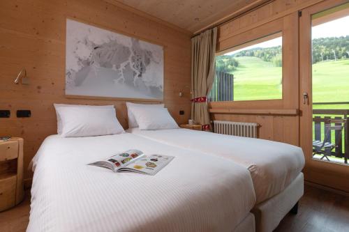a bedroom with a bed with a book on it at Hotel Funivia in Bormio