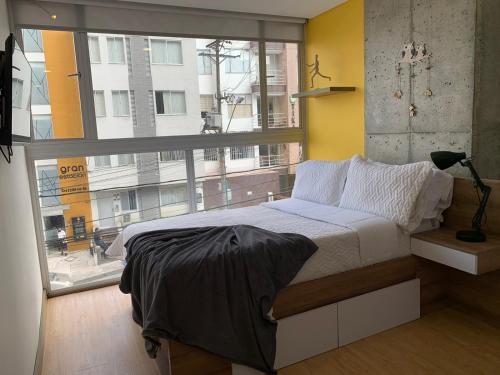 a bedroom with a bed and a large window at Ulivin Apartaestudios Manizales in Manizales
