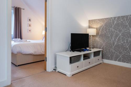a bedroom with a bed and a tv on a dresser at Trewhiddle Retreat V24 by Together Travel - Luxury 4-Bedroom Villa in St Austell