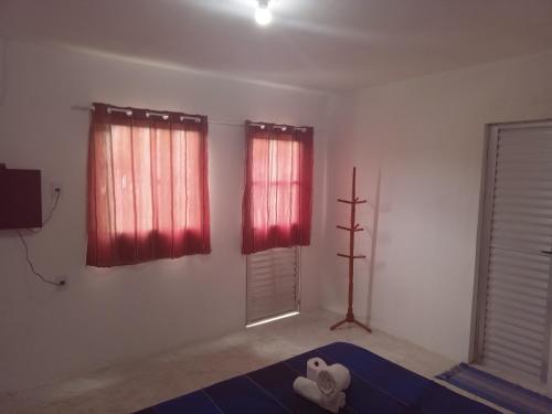 - un salon avec des rideaux rouges et une télévision dans l'établissement Pousada Sol de Imbassai, à Imbassaí