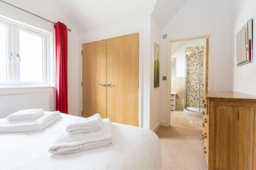 1 dormitorio con cama blanca y cortina roja en Trewhiddle Villa 18 en St Austell