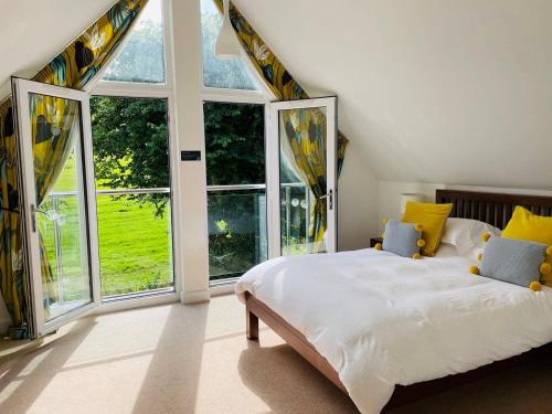 a bedroom with a large bed and large windows at Trewhiddle Retreat V20 by Together Travel - Luxury 3-Bedroom Villa in St Austell