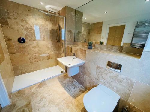 a bathroom with a sink and a shower and a toilet at Trewhiddle Retreat V20 by Together Travel - Luxury 3-Bedroom Villa in St Austell