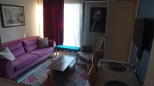 a living room with a purple couch and a window at ŞİRİNYER APART OTEL in Izmir