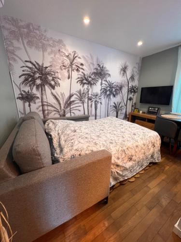 sypialnia z łóżkiem z palmami na ścianie w obiekcie T2 cosy / quartier calme / magasins d’usine a proximité w mieście Saint-Julien-les-Villas