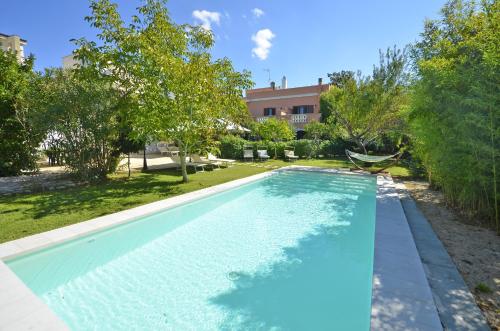 una piscina en un patio con árboles y un edificio en Villa Magnolia, en Morciano di Leuca