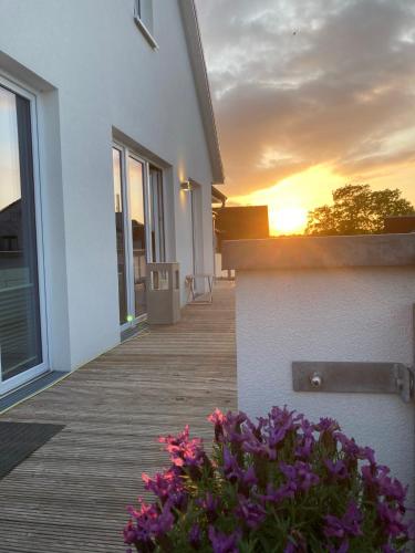 a wooden walkway leading to a house with purple flowers at Penthouse "Meerzeit" Kellenhusen mit Strandkorb in Kellenhusen