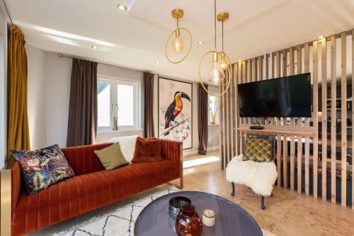 a living room with a red couch and a tv at Trewhiddle Retreat V5 by Together Travel - Luxury 4-Bedroom Villa in St Austell