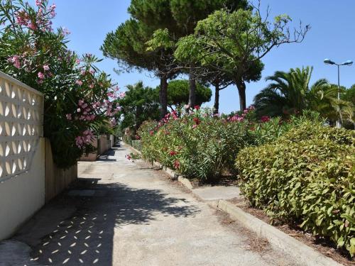 un jardin avec des fleurs et des arbres et un trottoir dans l'établissement Charmant Studio Mezzanine - Climatisé, Terrasse BBQ, Proche Plage et Commerces - 4 Couchages - FR-1-229-809, à Gruissan