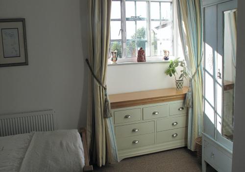 a bedroom with a bed and a dresser with a window at Corve Cottage Historic cottage in beautiful ludlow in Ludlow