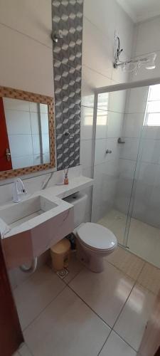 a bathroom with a toilet and a sink and a shower at prx à praia com piscina in Mongaguá