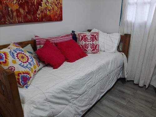 Una cama con almohadas rojas y blancas. en Sol de Chacras en Luján de Cuyo