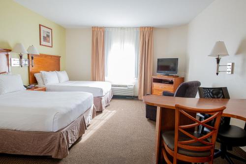 a hotel room with two beds and a desk at Candlewood Suites New Iberia by IHG in New Iberia