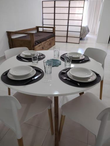 una mesa blanca con platos y vasos. en ALHE del Norte en San Miguel de Tucumán