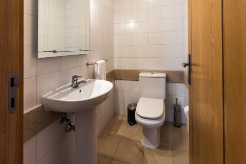 a white bathroom with a toilet and a sink at Acacia Apartment by Atlântica in Funchal