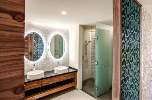 a bathroom with two sinks and two mirrors at Palmaïa The House of AïA All Inclusive Wellness Resort in Playa del Carmen
