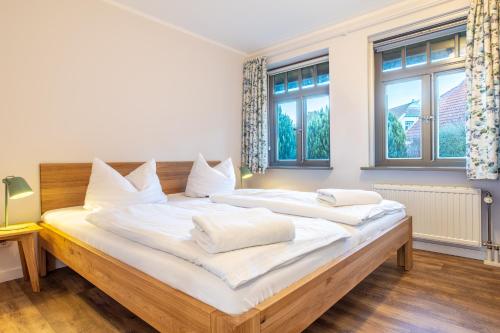 um quarto com uma cama grande com lençóis brancos e almofadas em Ferienhaussiedlung Strandperlen Buchenhof 2a (Typ VIII) em Wustrow