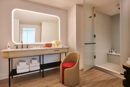 a bathroom with a sink and a mirror and a chair at Virgin Hotels New York City in New York